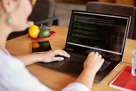 带笔记本电脑的开发人员程序员肩部照片的后视图屏幕上的程序代码和脚本数据戴眼镜的年轻自由职业者图片