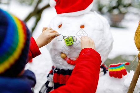 小孩把眼镜戴在雪人身上图片