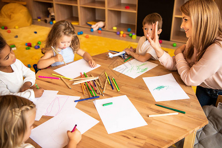 在幼儿园教多民族儿童数和用手指显示数字的微笑教育者图片