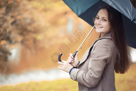 中秋卡通雨中秋天公园里穿着外套的年轻女孩背景