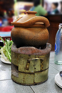 泰国亚洲泥锅旧壁炉上的蘸锅汤中的甜辣椒蘸锅用香料在木板上的泥锅炖图片
