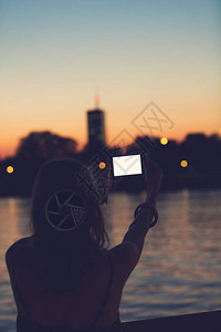 在城市城市环境中使用手机的女孩靠近河流图片