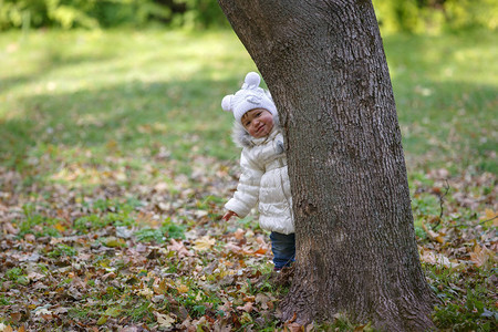 小女孩躲在树后在绿叶公图片