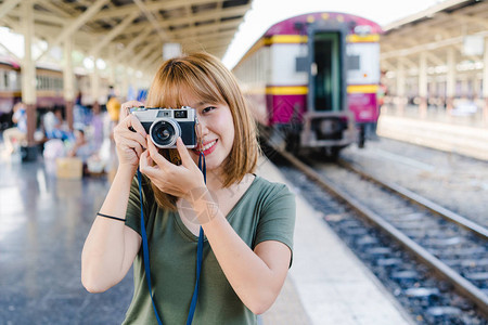 快乐的旅行者背包客亚洲女在泰国曼谷火车站旅行时使用相机拍照假期概念的图片
