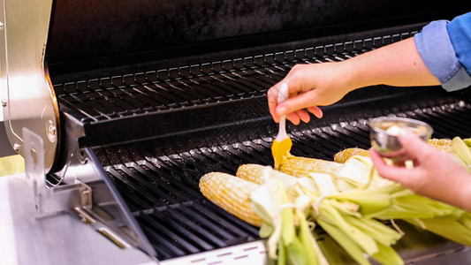 将新鲜有机玉米放在户外燃气烤架上图片