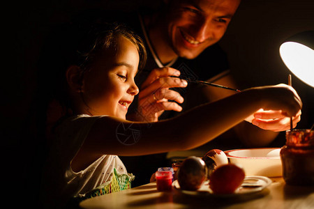 欢笑的父亲和小女儿在桌边吃着复活图片
