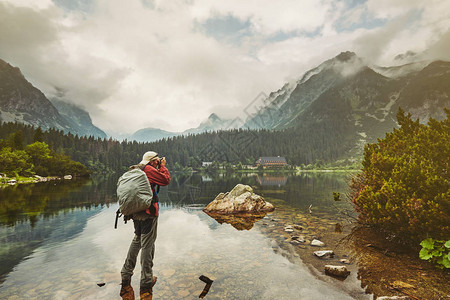 野生动物的迷人之美水晶湖绿色森林和云雾缭绕的山脉站在湖边的摄影师正在图片