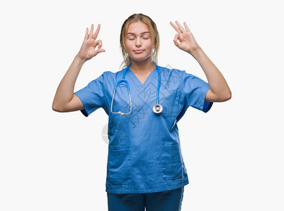 身穿外科医生制服的年轻白人医生女人在孤立的背景下放松图片