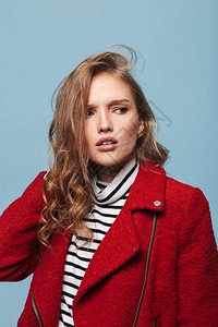 身穿红色夹克的长发卷毛的年轻严肃女人的肖像图片