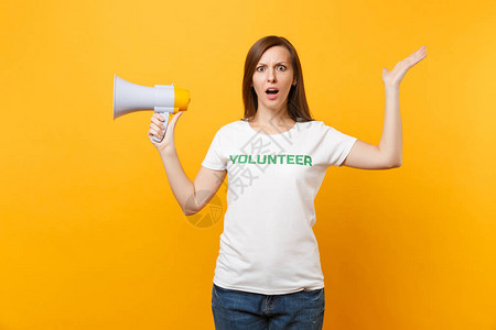 身穿白色t恤的女肖像写着绿色标题志愿者在黄色背景上隔离的公共广播扩音器中尖叫自愿无偿帮助图片