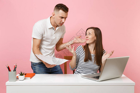 两个愤怒的年轻女商人同事坐在白色办公桌前工作图片