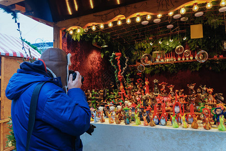 男子在德国柏林冬季威廉皇帝纪念教堂圣诞市场的摊位上拍照AdventFair装饰和集市上图片