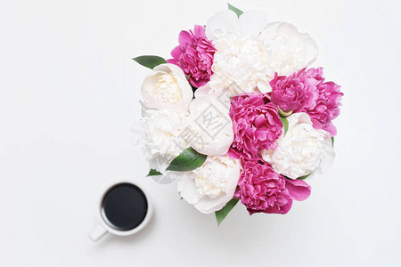白桌背景上有一杯咖啡和白花及粉红小马花的工作场所图片