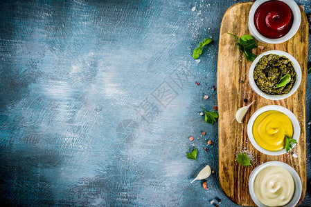 四种经典酱汁番茄酱蛋黄酱芥末香蒜酱配香草和香料蓝色混凝土背景顶图片