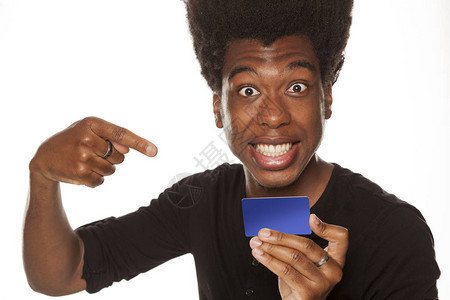 指着一张白背景信用卡的非洲美国年轻人微笑而快乐图片