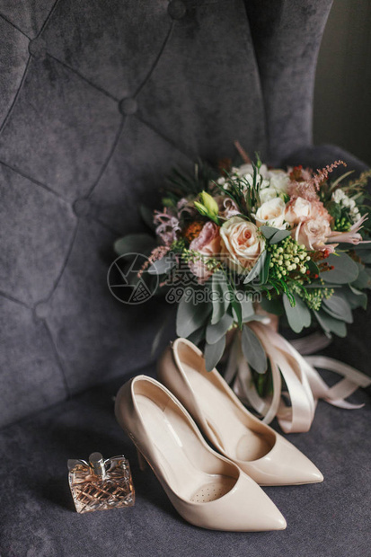 现代婚礼花束蜜鞋和香水瓶放在时尚的灰色沙发上现代日流行新娘饰图片