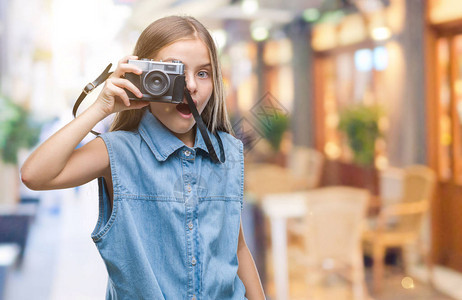 年轻漂亮的女孩在与世隔绝的背景下用老式相机拍照图片