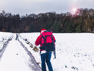 运动型圣诞老人背着包走在白雪覆盖的田野上积极健康的生活方图片