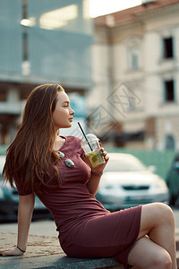 在街上喝清新柠檬水的冷漠微笑的女人城市早间概念图片
