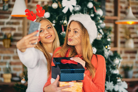 女朋友们站在圣诞树前自拍和拿着礼物圣诞节图片