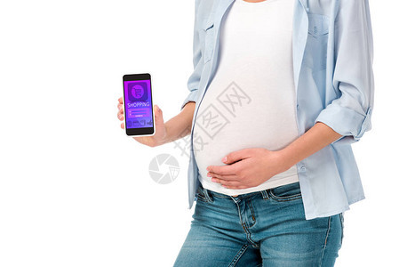 孕妇展示智能手机时用白色孤立的购物器械观看白衣图片