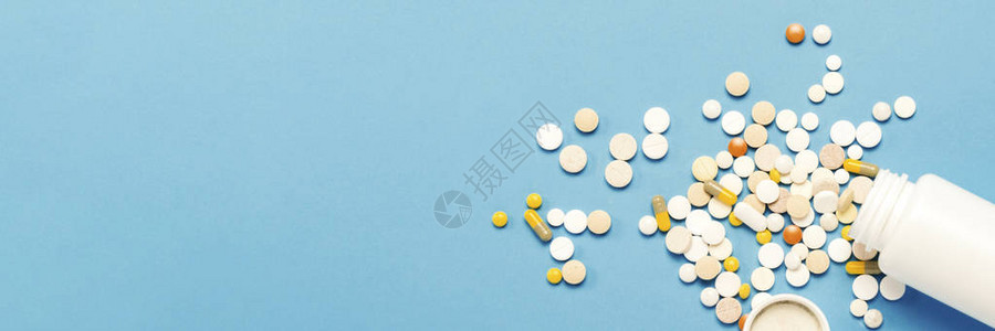 蓝色背景上的白色瓶子和多色药丸药物药物药物和疾病治疗的概念横幅图片