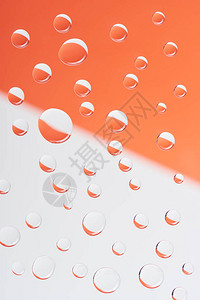 白色和橙色背景的透明平静水滴近图片