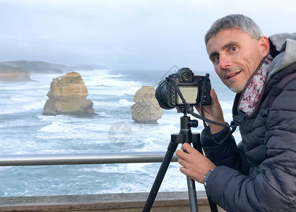 有三脚架摄影机的人在澳洲十二个使者之间拍摄美背景图片
