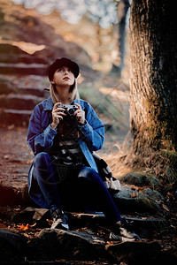 带着古董相机的金发年轻女孩在秋天的时候在公园休息了图片
