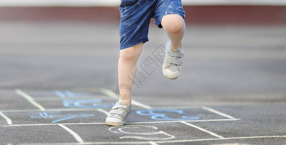 小男孩的腿和在沥青上绘制的跳房子的特写镜头图片
