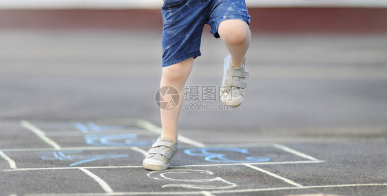 小男孩的腿和在沥青上绘制的跳房子的特写镜头图片