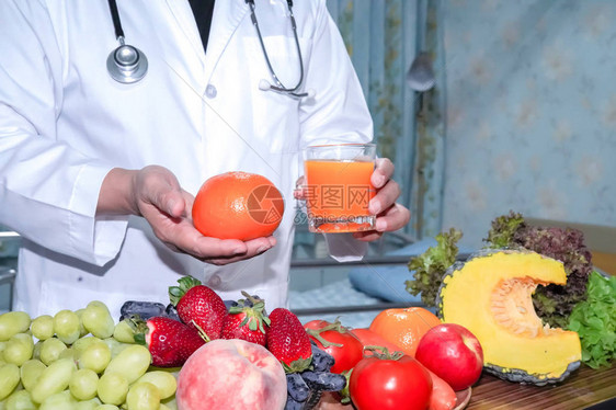 营养学家医生将橙汁与草莓土豆苹果李子葡萄胡萝卜桃子南瓜和沙拉蔬菜放在桌上图片