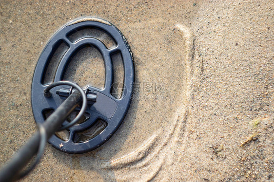 沙子里的金属探测器在海滨寻找珠宝图片
