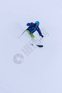 在新鲜的粉雪上背着包滑雪下坡的自由式滑雪者图片