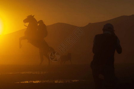 一名牛仔用脚骑马在日落时双脚停留图片