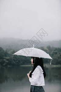 雨天在湖边拿着雨伞看着亚洲图片