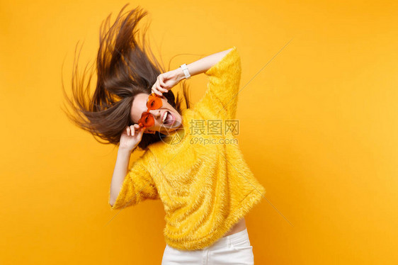 穿着毛皮衣的兴奋少女拿着心橙色眼镜在演播室里玩弄于股掌中跳跃图片
