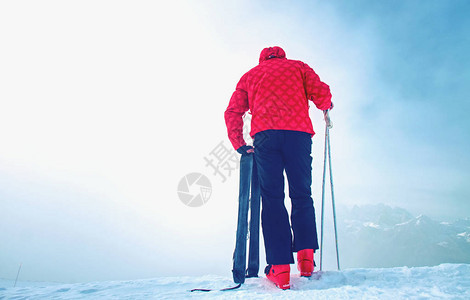 满身红黑的高塔滑雪机双脚大手拿着滑雪杆站在冰雪深图片