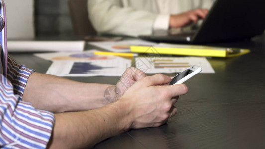 一个商人使用他的智能手机打字消息坐在办公室技术移动运营商通信互联网在线社交媒体用户连接的图片