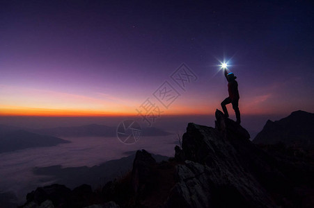 登山者或背包者在日落时站在岩石山峰上图片