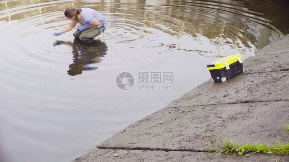 测量城市河流中pH值水分的女生态学家图片