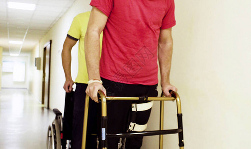 穿着矫形器的年轻残疾人手持步行架穿过康图片
