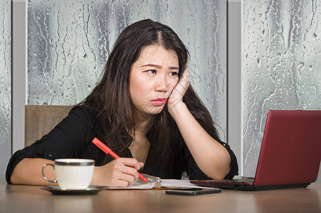 年轻美丽悲伤和沮丧的亚洲韩国女商人在办公室桌前工作疲惫和沮丧图片