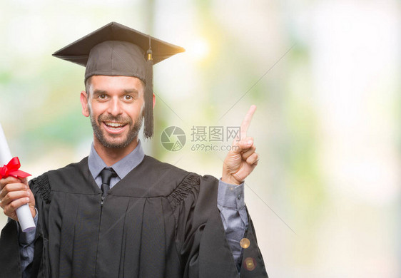 年轻英俊的毕业男子在孤立的背景下持有学位图片