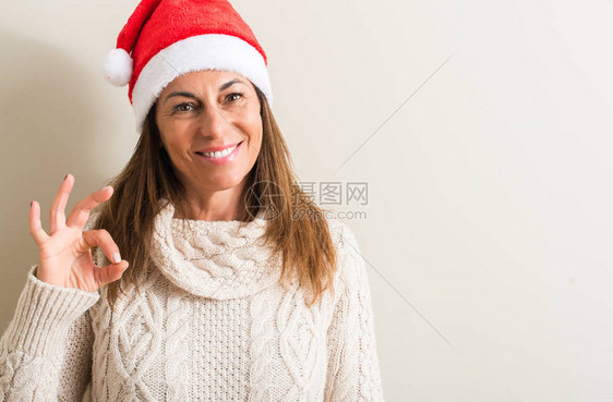 中年妇女戴着圣诞卡萨斯帽用手指做好标记图片