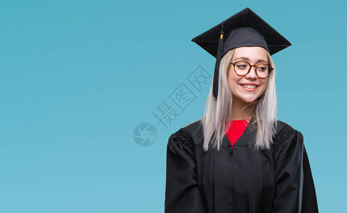 身穿毕业制服的金发年轻女郎与孤立的背景相距甚远图片