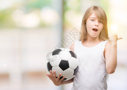 年轻的金发蹒跚学步的孩子拿着足球图片