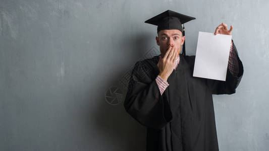 年轻的红发男子在灰色的格朗基墙上穿着毕业制服图片