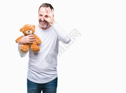 中年白发老人抱着泰迪熊在孤立的背景下图片