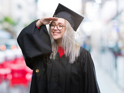 身着毕业制服的金发年轻女子在孤立的背景中非常快乐图片